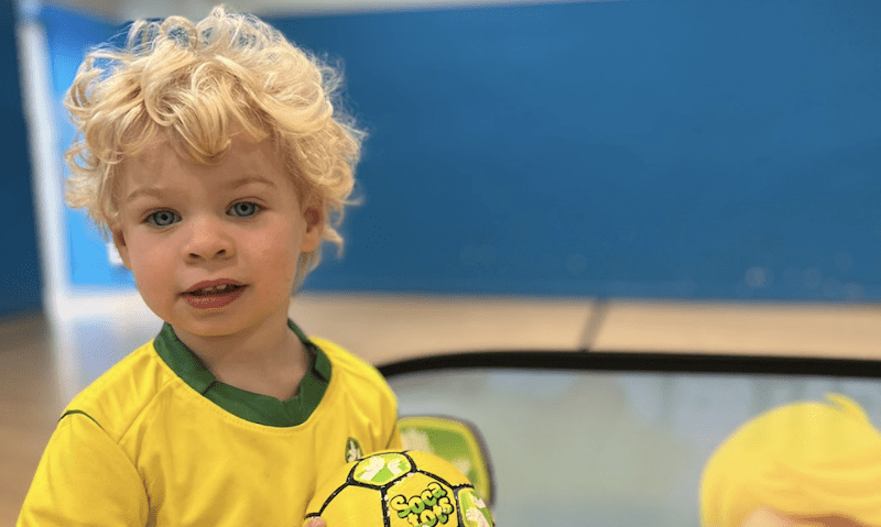Toddler football classes near me. Image shows a young toddler holding a socatots football.