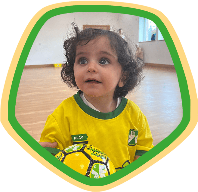 Image shows a child holding a Socatots football during a class