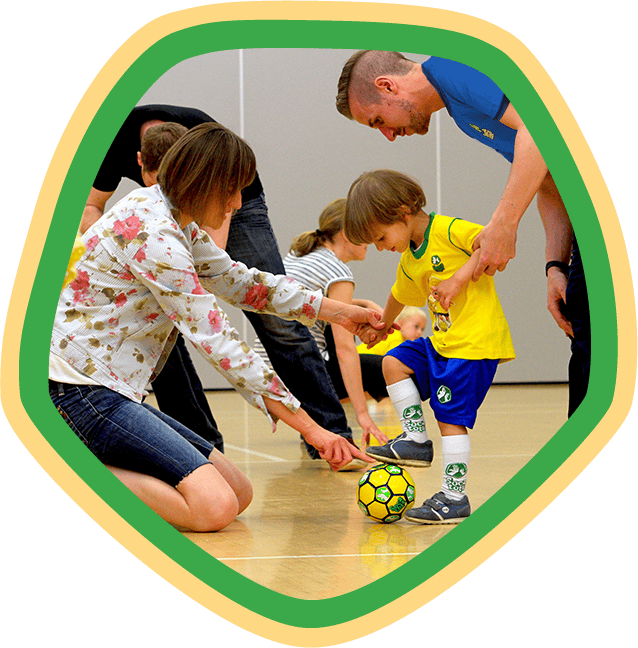 Toddler with a football being helped by their parent and our SOCATOTS coach