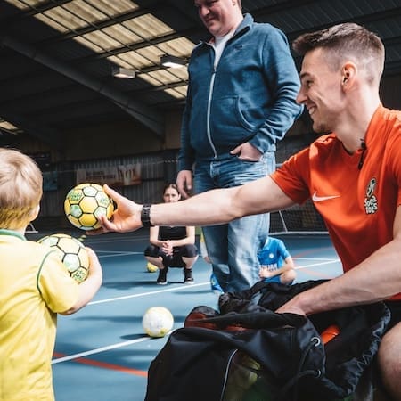 Coach holding football with Socatots kid