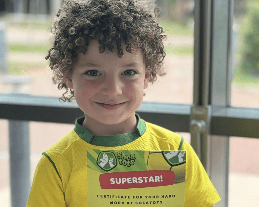 First football session. Image shows a child holding a superstar certificate after attending a Socatots football class.