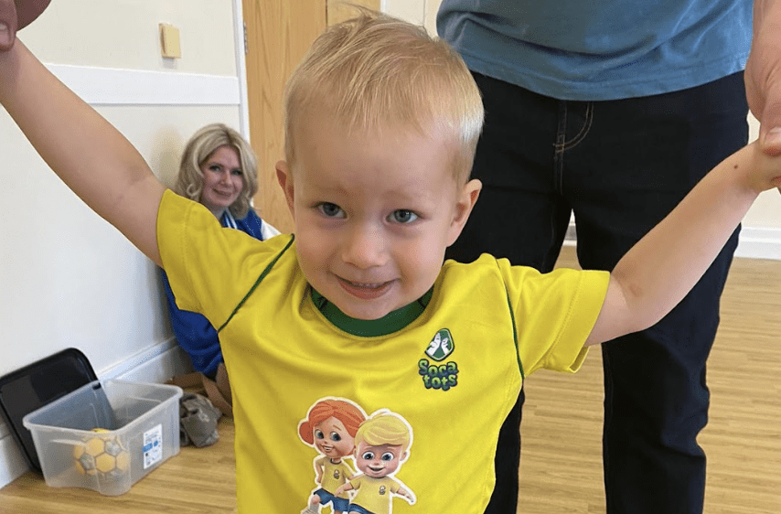 Can children head the ball during football. Image shows a young boy smiling during a Socatots class.