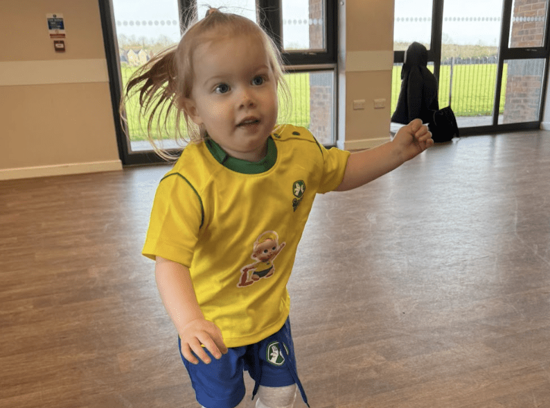 Indoor activities for toddlers. Image shows a toddler taking part in a Socatots class. 