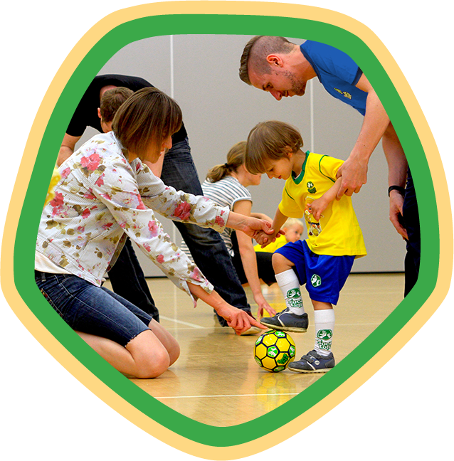 Toddler with a football being helped by their parent and our SOCATOTS coach