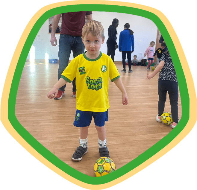 Image shows a boy during a Socatots class learning how to dribble a Socatots football