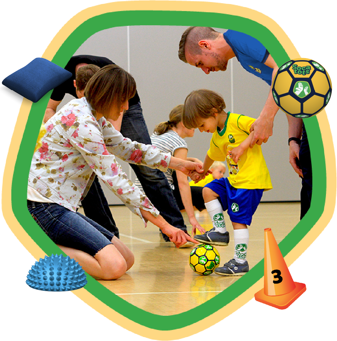 Toddler with a football being helped by their parent and our SOCATOTS coach