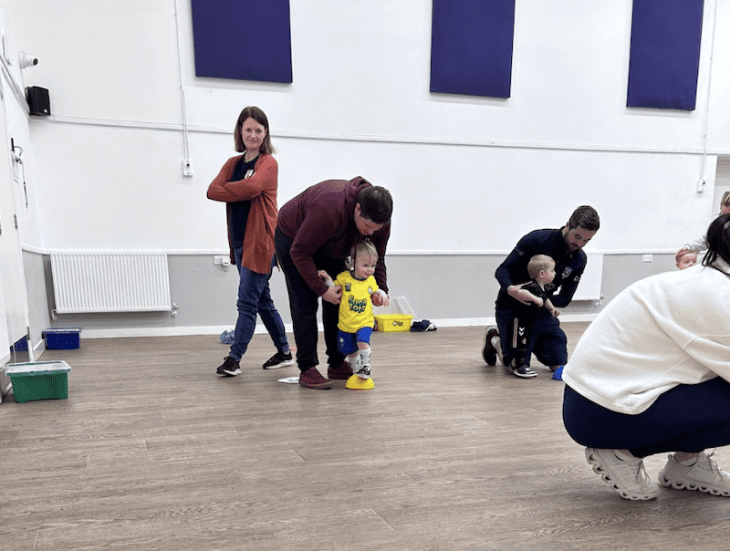 Toddler football club in Selby. Image shows a toddler with his dad taking part in the Socatots class and other parents and toddlers around them. 