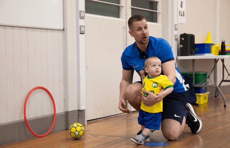Toddler football. Image shows a Socatots coach introducing a toddler to football skills. 